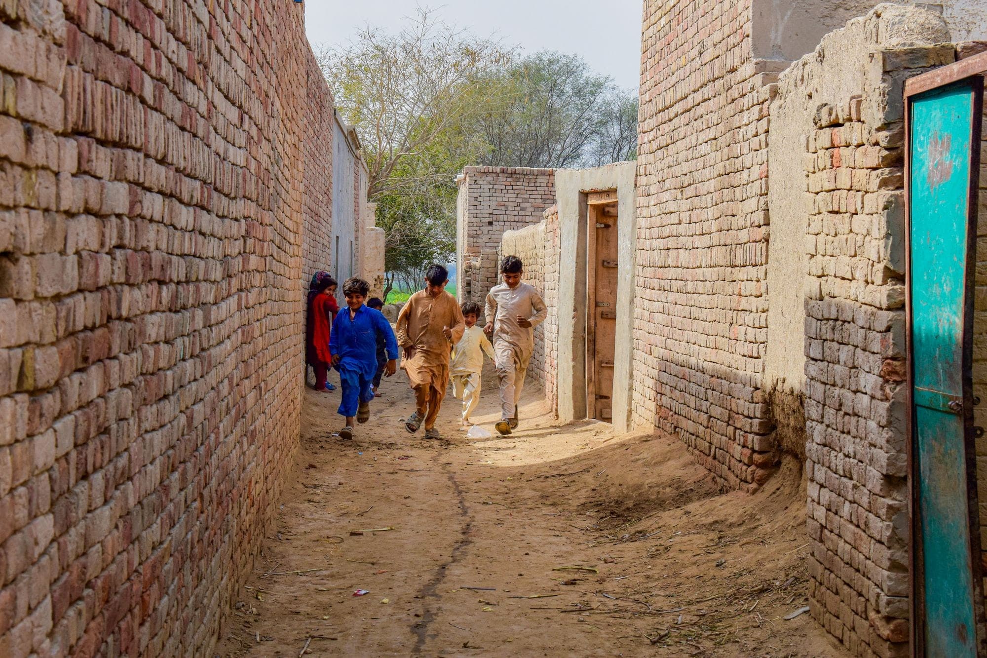 Children walking through a narrow alley between brick walls
