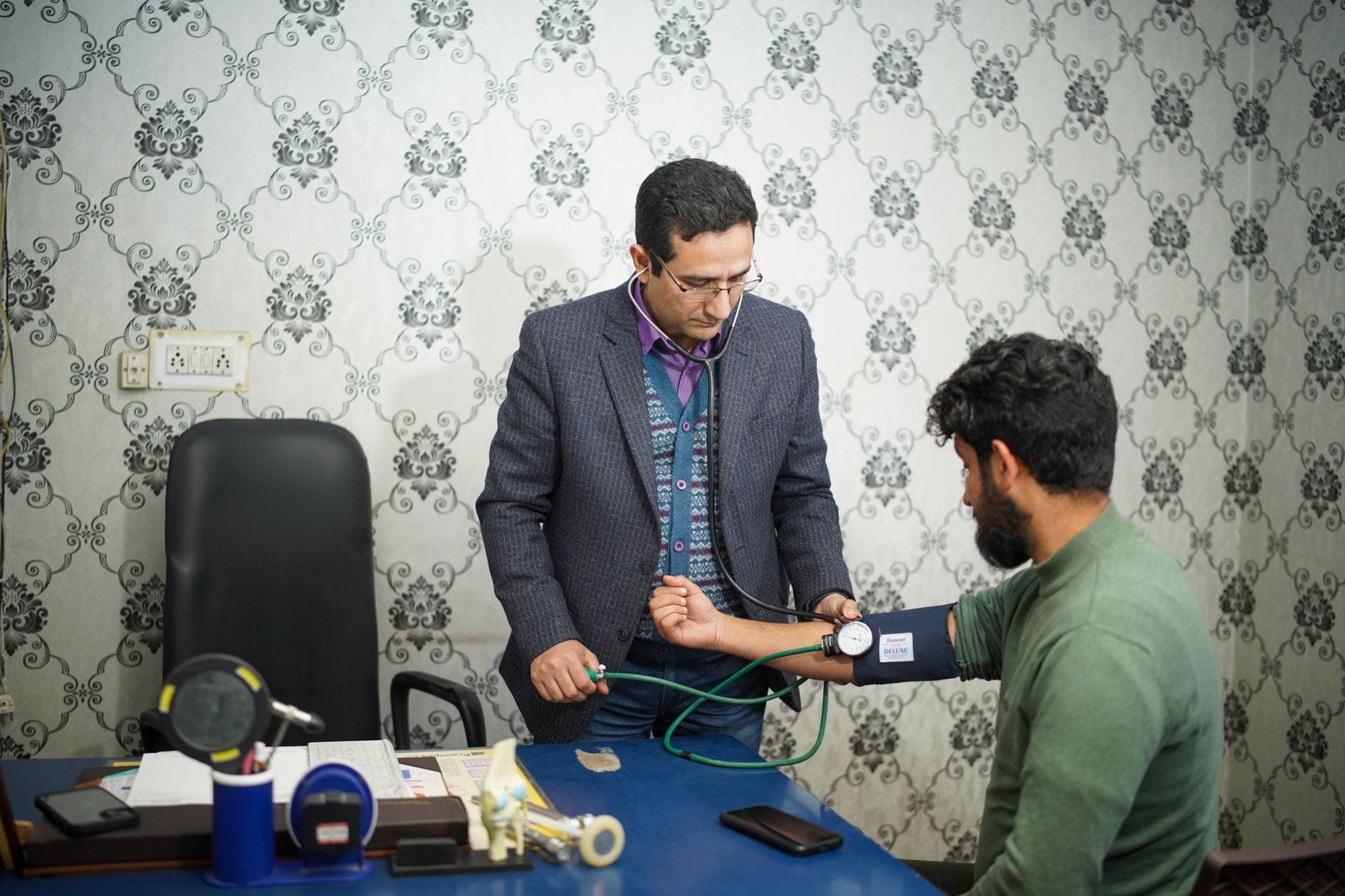 A doctor taking a patient's blood pressure in a small clinic